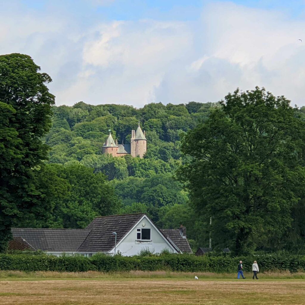 Castell Coch nestled in Fforest Fawr with dog walkers in the foreground